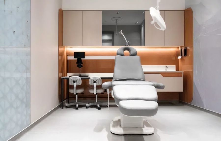 Elegant treatment room at Cosmedica Aesthetic Clinic Istanbul with a gray reclining chair, copper-toned cabinetry, and medical lighting, used for rhinoplasty procedures.